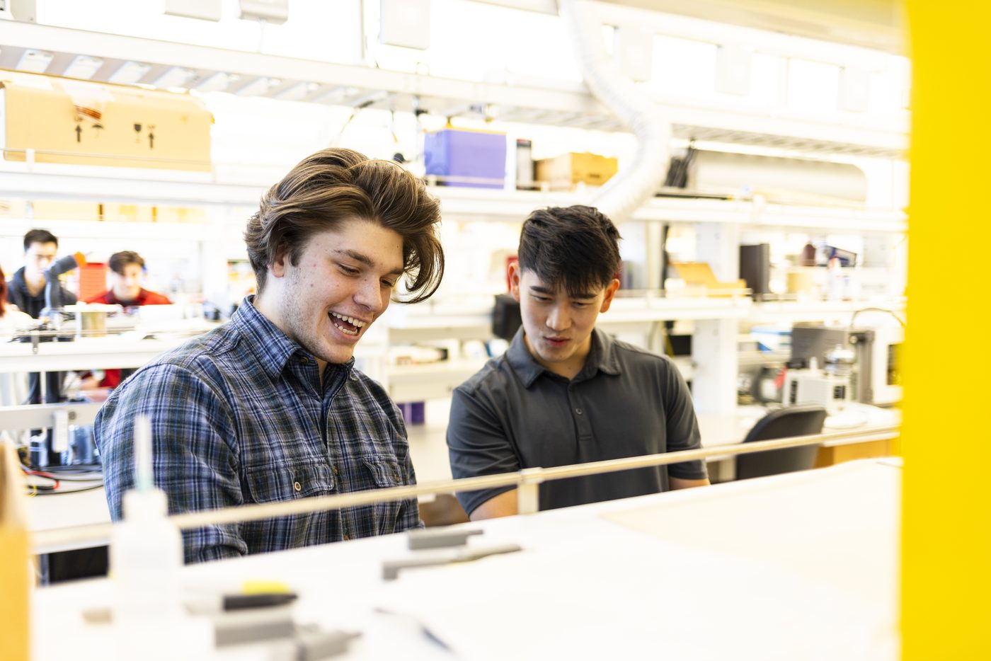 Benjamin Price laughing with a colleague while working at a bench in a bright open laboratory.