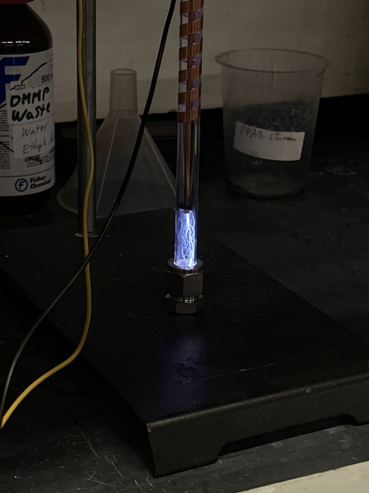 A glass discharge tube glowing violet-white on a dark laboratory bench.