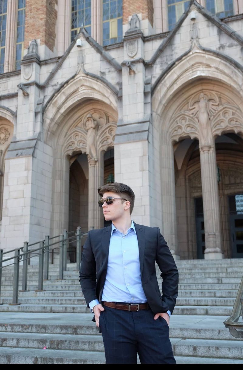 Benjamin Price in a suit outside a Gothic stone building on the University of Washington campus.