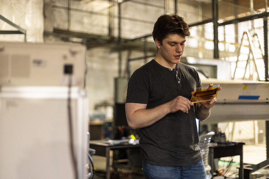 Benjamin Price inspecting a dielectric barrier discharge actuator test article in the lab.